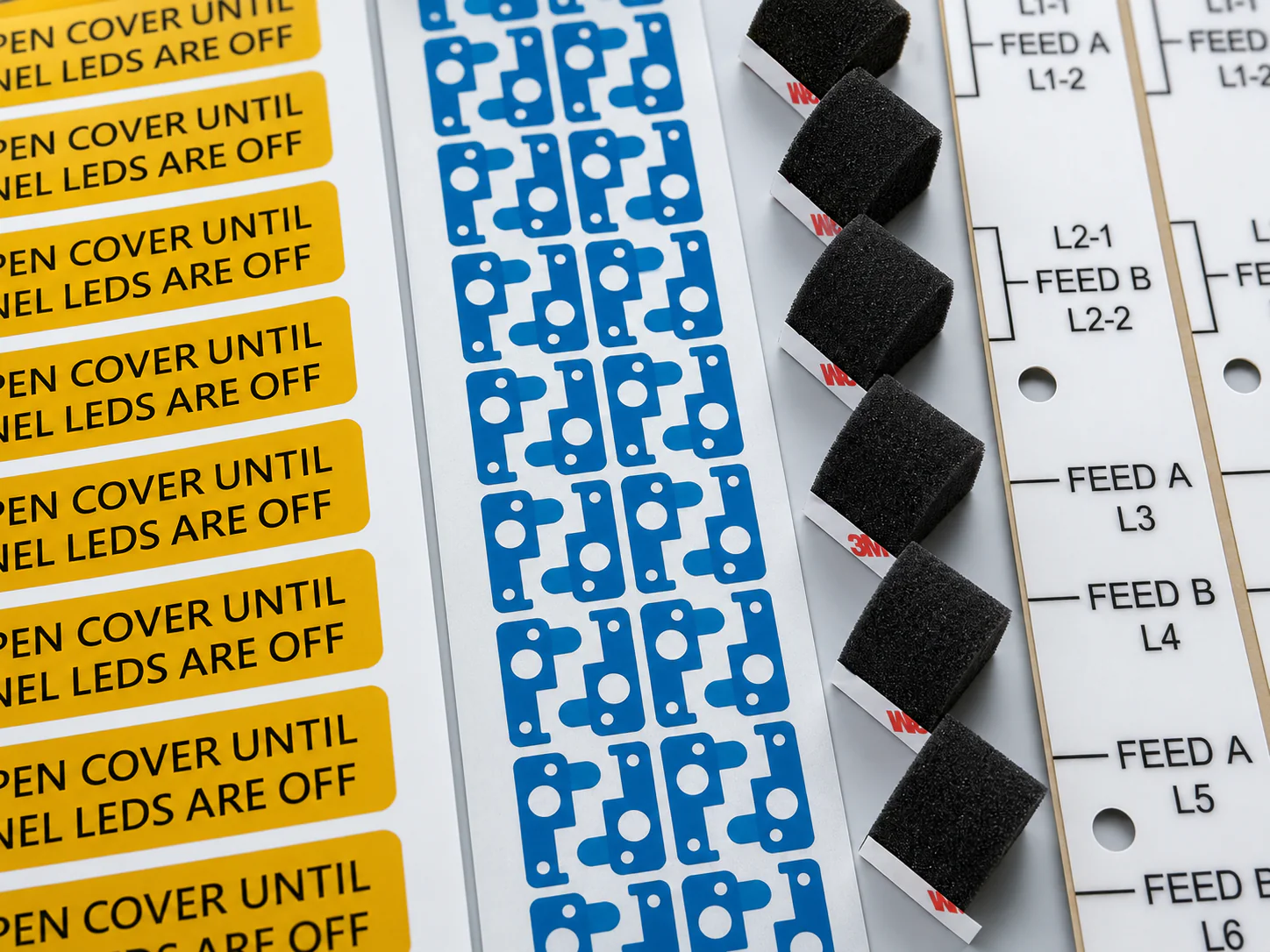 Printed warning labels, protective die-cut films, cushioning foams and identification components for industrial control assemblies