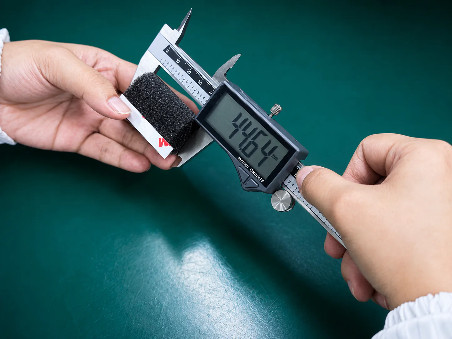 Dimensional verification of an adhesive-backed cushioning foam component using a digital caliper